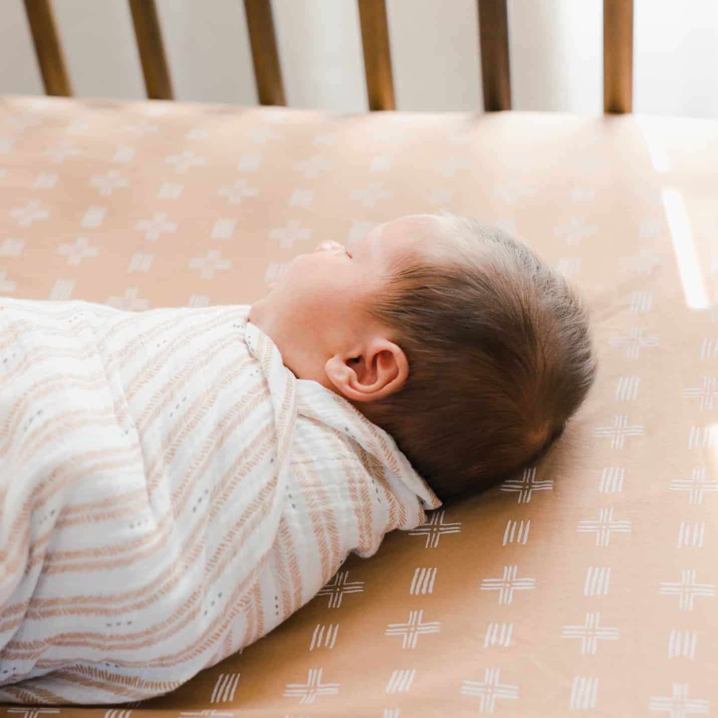 baby in swaddle in a crib sleeping
