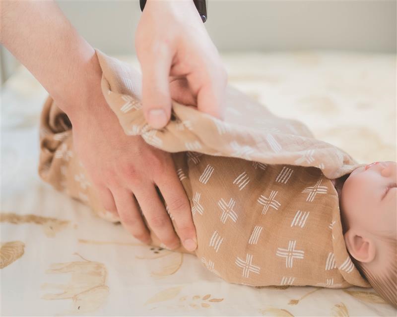 hands swaddling baby crane baby swaddle wrap