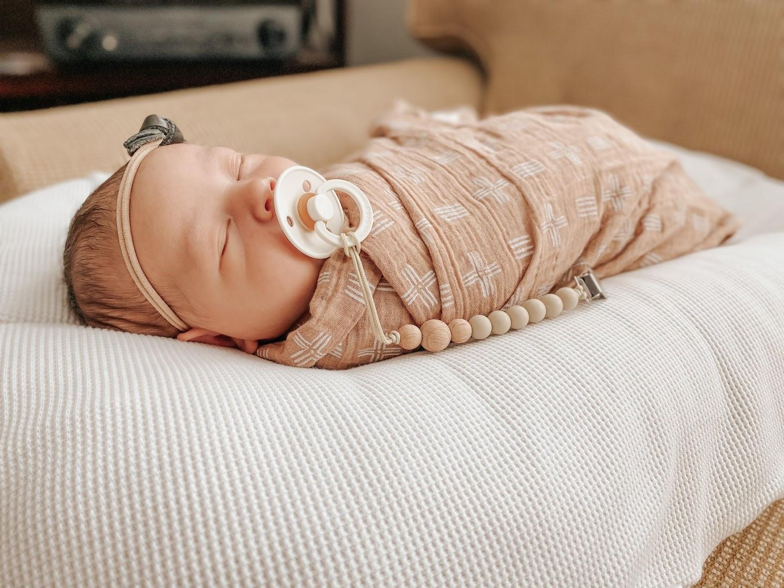 Swaddled baby laying down with a pacifier