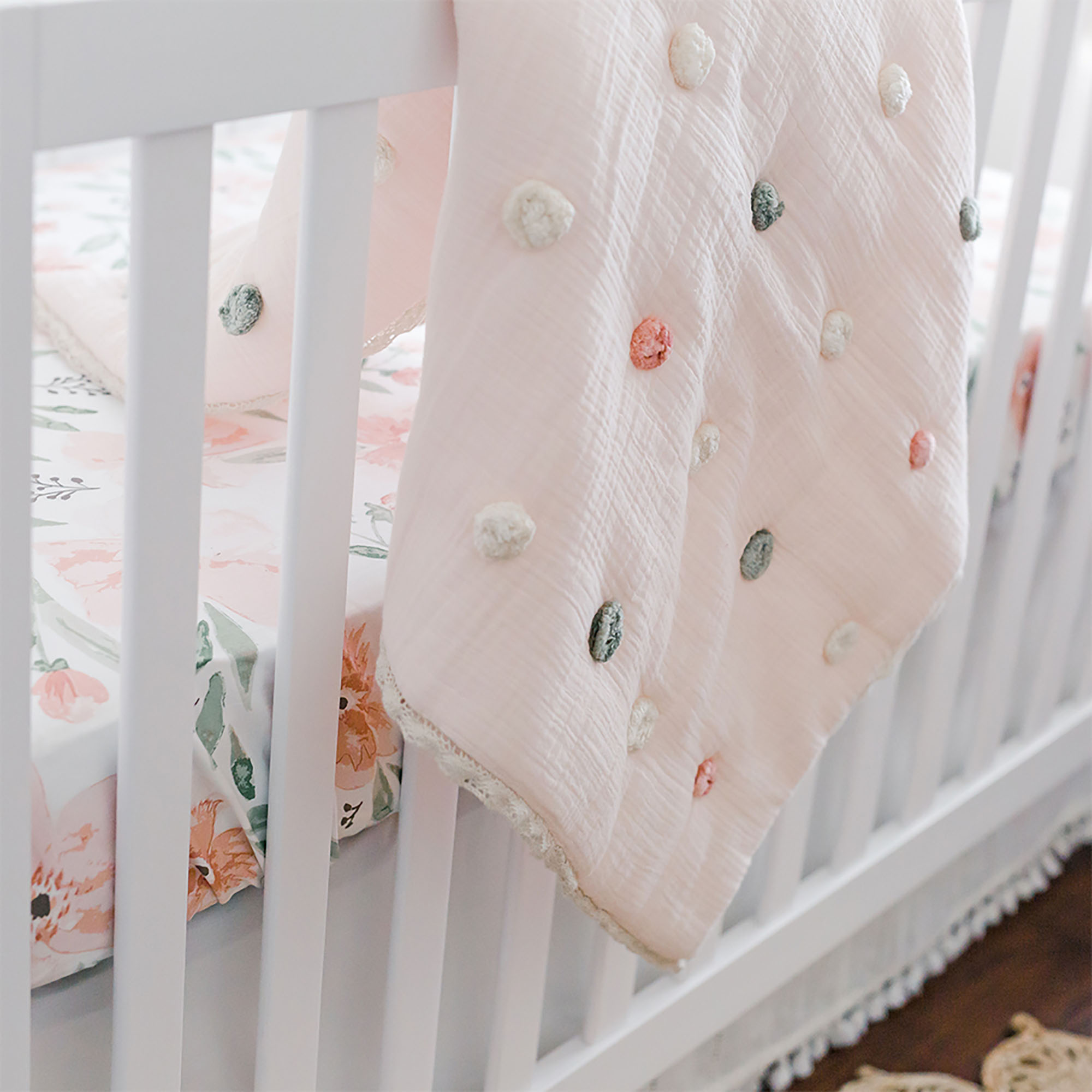 Pom pom blanket draped over crib bars