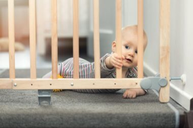 Crawling baby holding a baby gate
