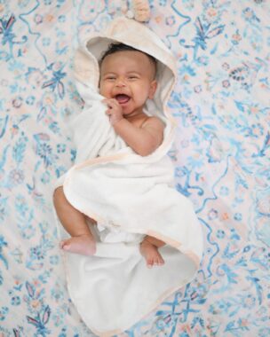 Happy baby wrapped in a hooded towel