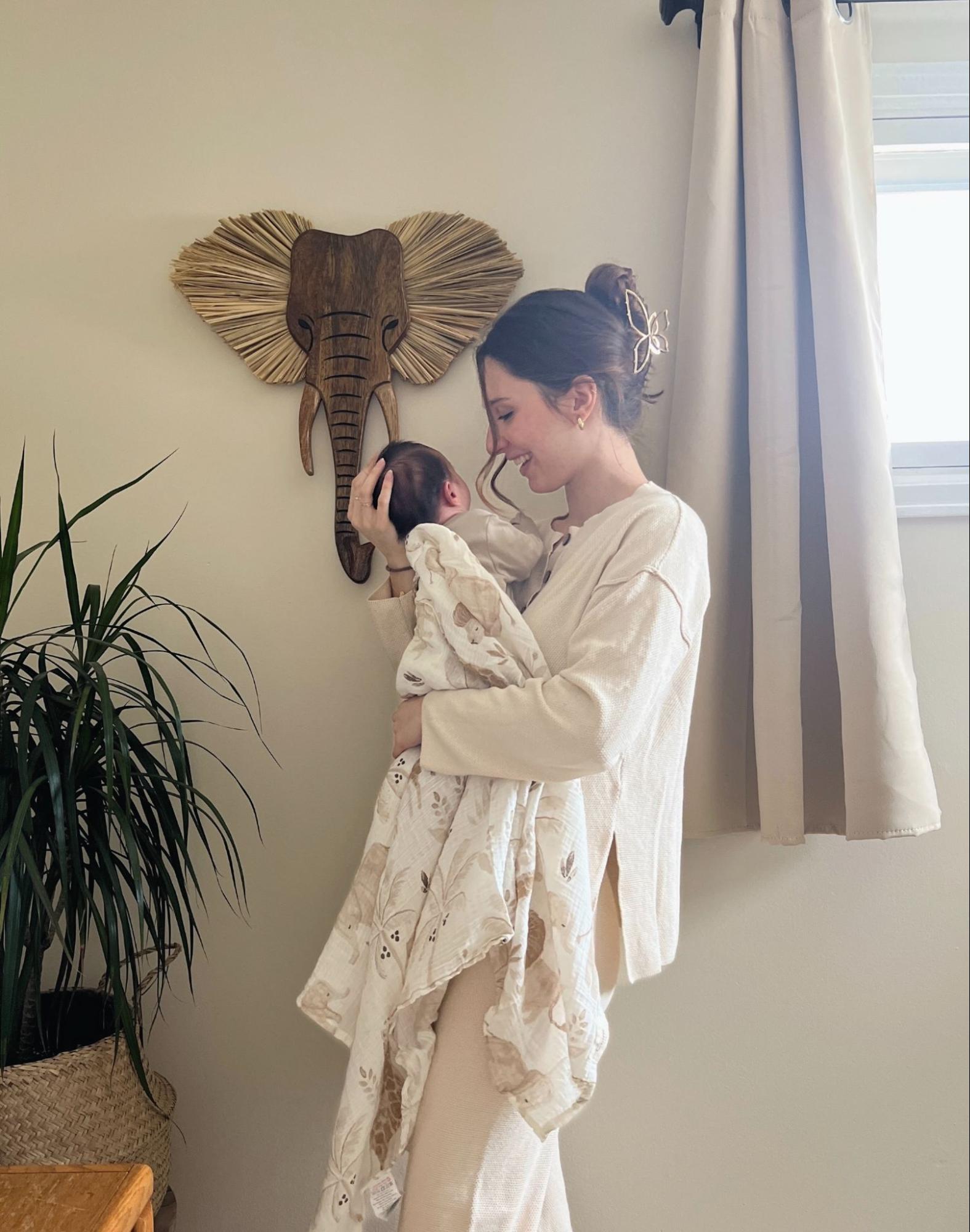 Mom carrying a baby wrapped in a swaddle blanket