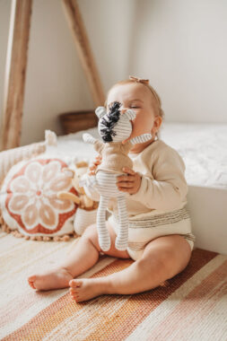 Baby bitting a zebra plush toy