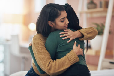 Two young women embracing each other at home