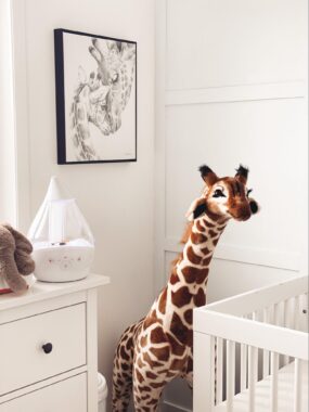 Large plush giraffe in a the corner of a nursery