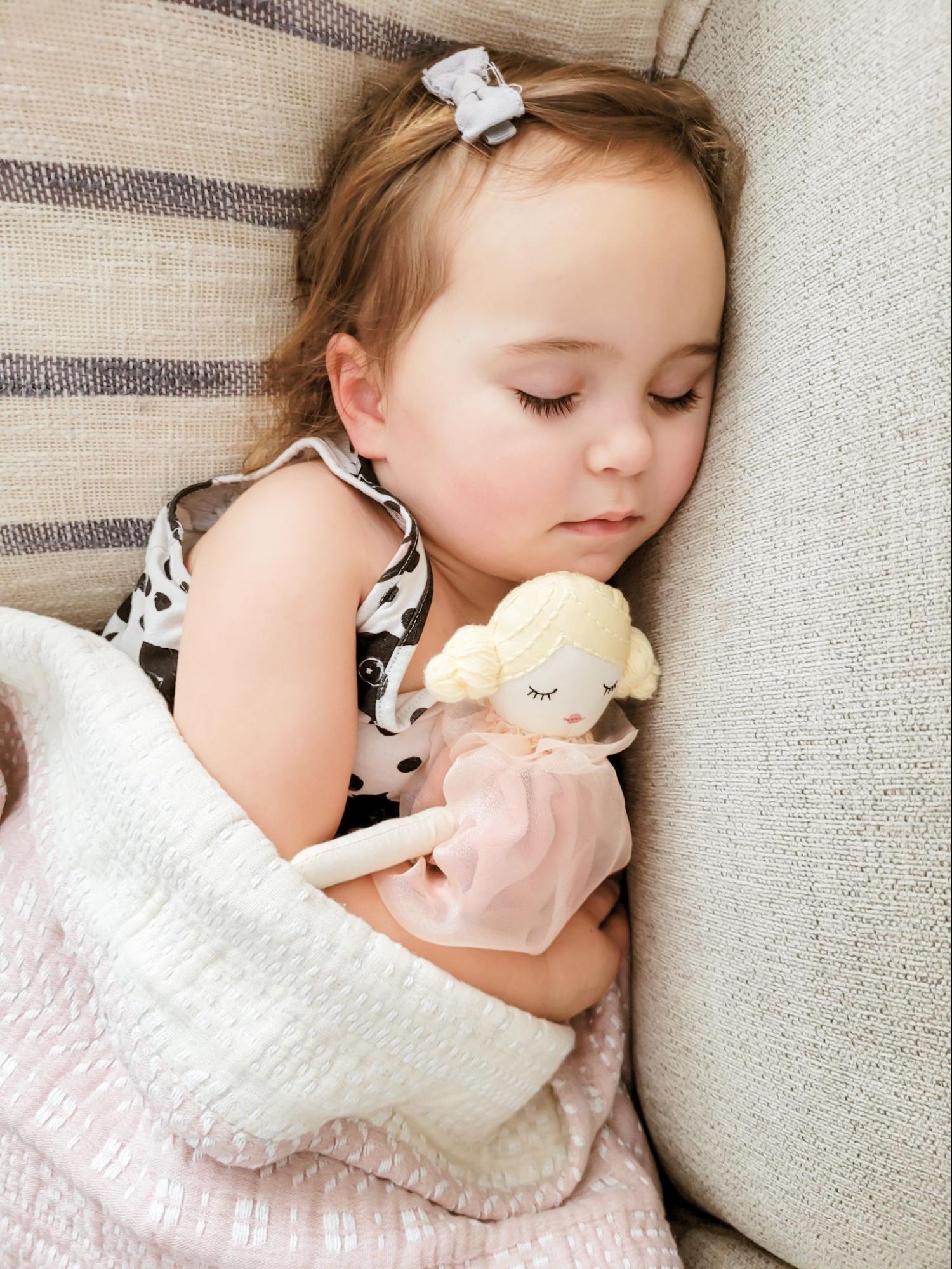 Baby sleeping snuggled up with a plush doll
