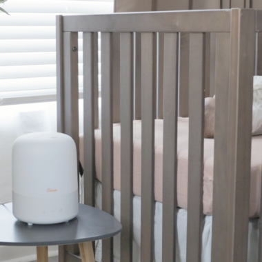 Baby humidifier and sound machine on a table next to a crib