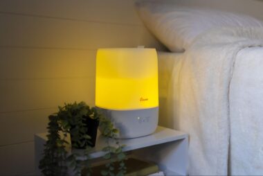 Humidifier with night light on a night stand next to a bed