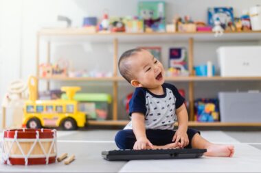 Happy baby playing with an electronic piano toy