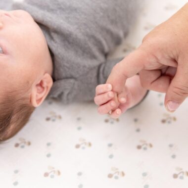 Close up of a baby holding mom's finger