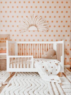 White crib against a pink polka dot wall