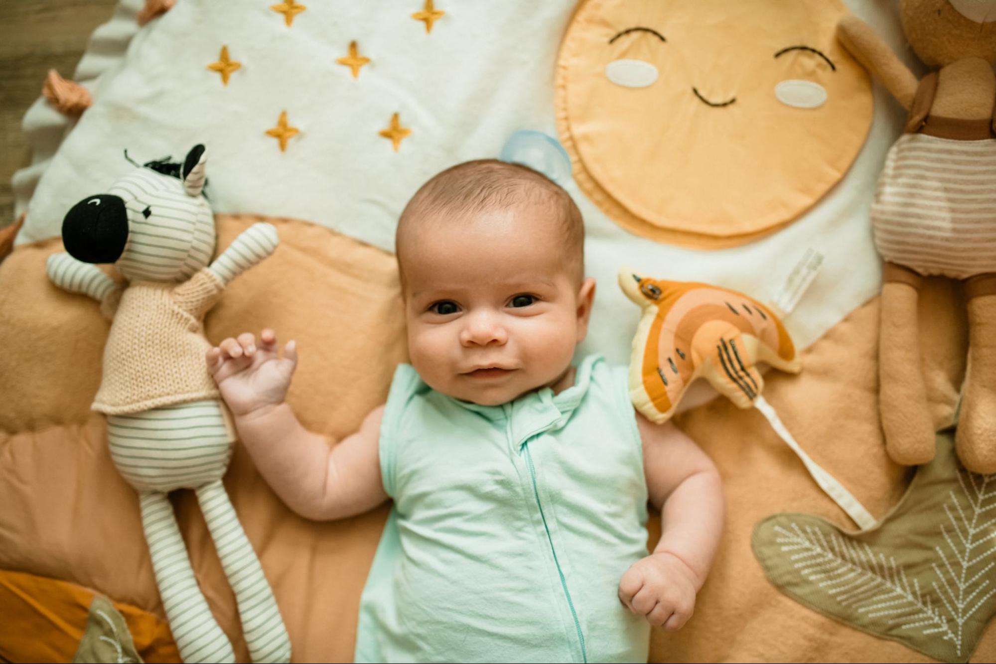 Baby laying on a play mat and looking at the camera
