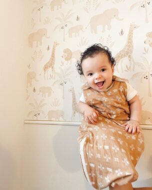 Smiling baby being held up and wearing a wearable blanket