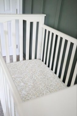 White crib with leaf pattern fitted sheet