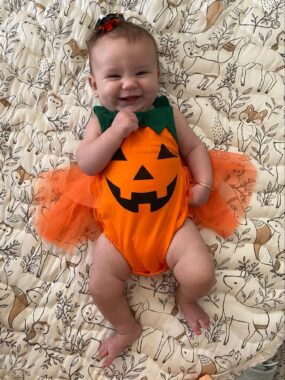 Smiling baby wearing a jack-o-lantern onesie