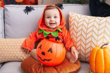 Baby wearing a jack-o-lantern costume with a candy pail