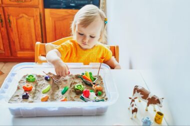 Toddler girl playing in a farm themed sensory bin