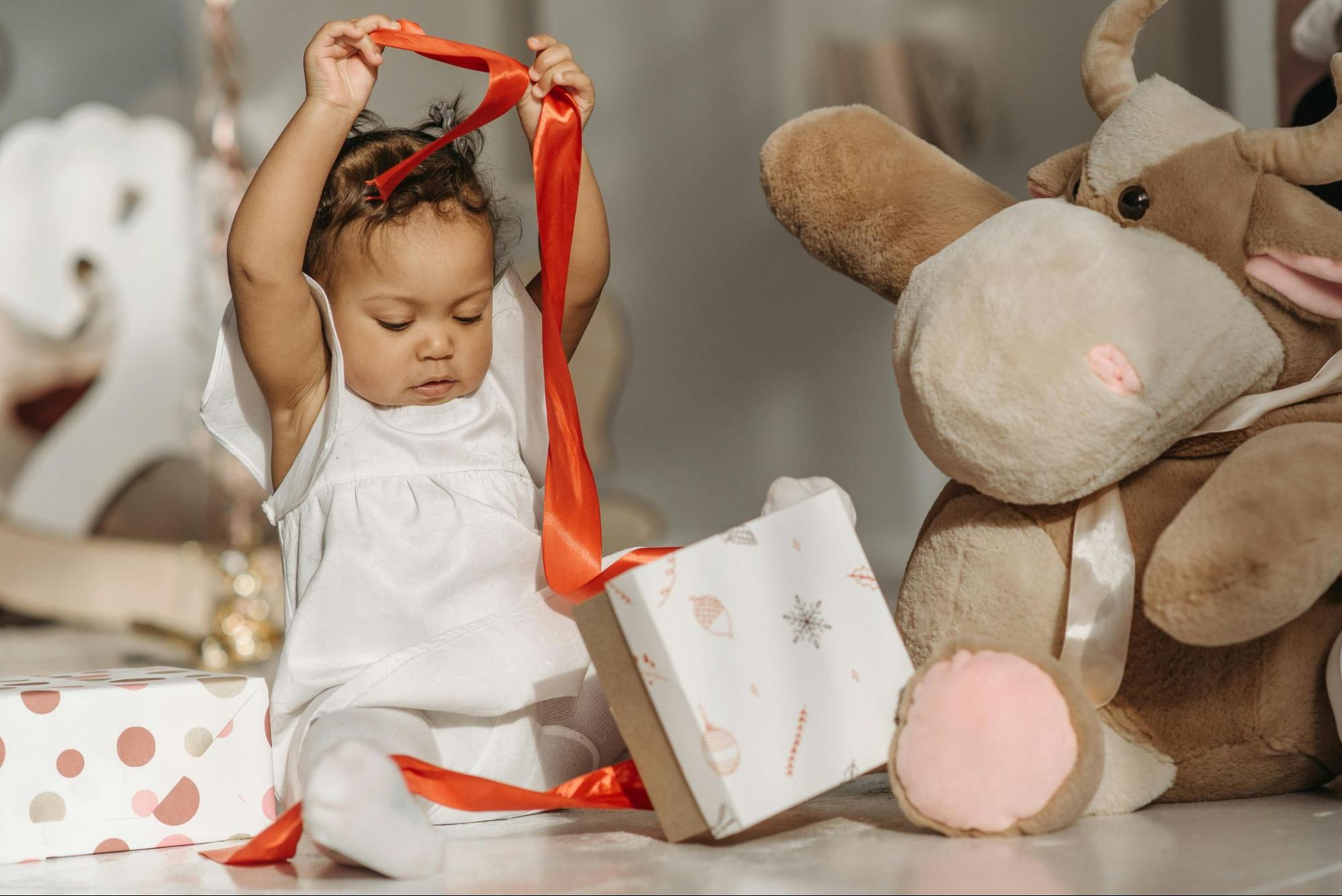 Baby girl taking a red ribbon off a present