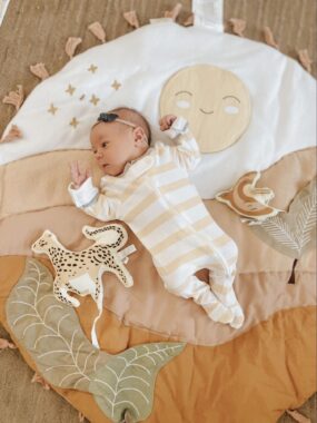 Baby girl lying down on a safari themed play mat