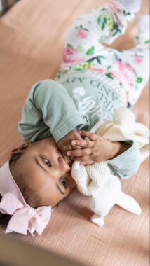 Baby girl lying down and chewing on a bunny lovey