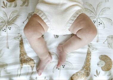 Close up of a baby lying down on a safari crib sheet