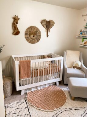 Neutral nursery with a white crib, rocking chair and safari animal wall art