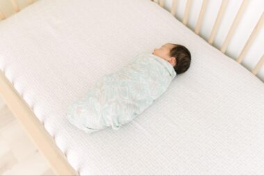 Overhead view of a baby swaddled and asleep in a crib
