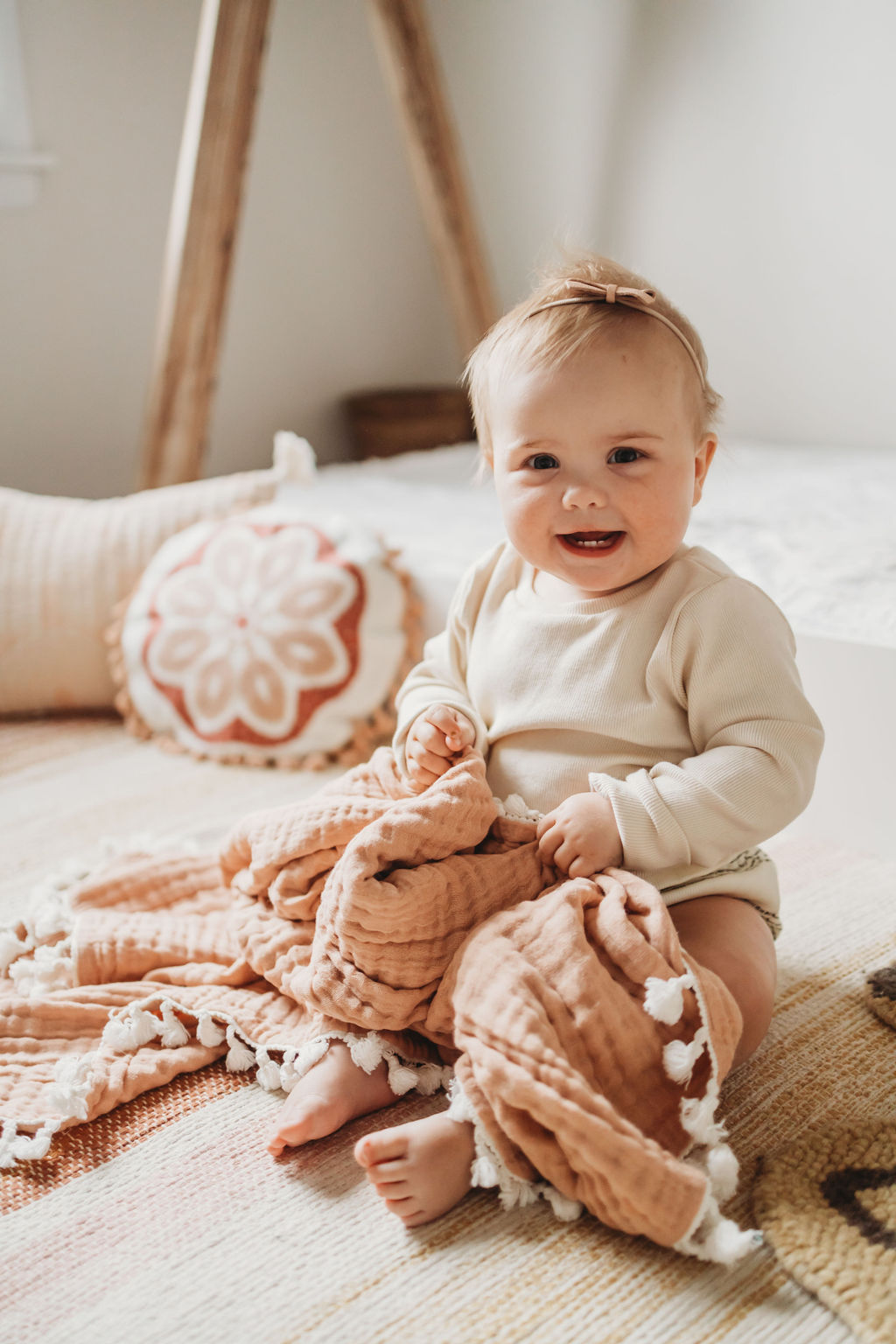 Smiling baby girl sitting on a rug and holding a blanket