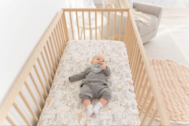 Baby laying down in a crib and looking to the side