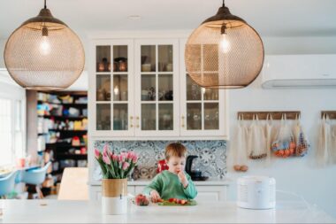 Little boy eating strawberries on the table next to an air purifier
