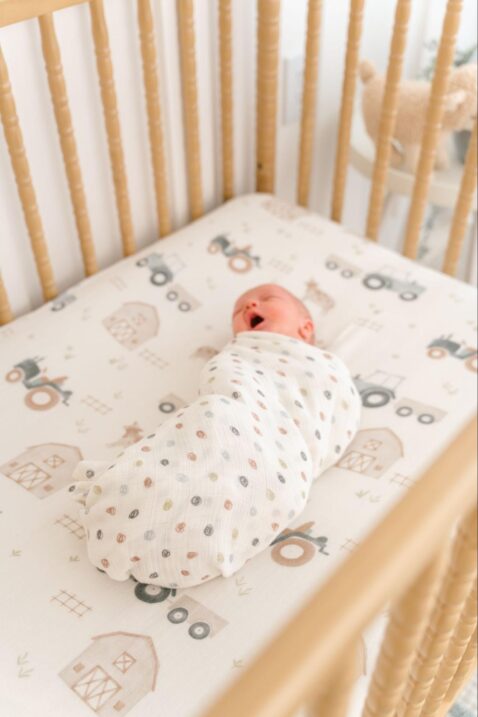 Swaddled baby yawning in a crib