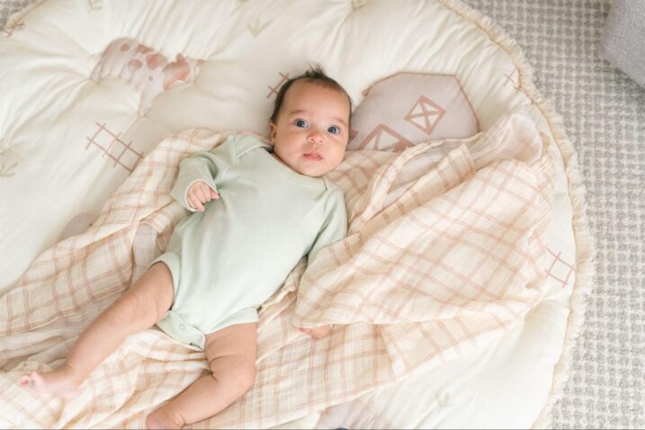 Baby lying down on a swaddle and playmat