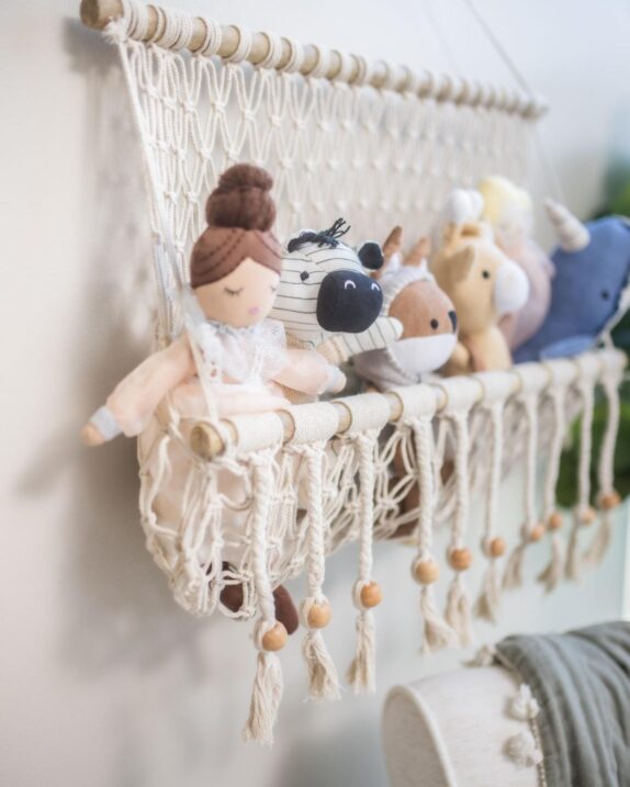 Hanging macrame basket full of plush dolls and stuffed animals