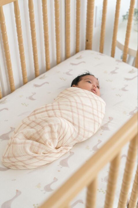 Swaddled baby lying in a crib