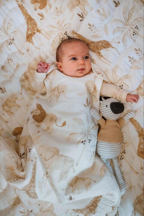Baby lying on a play mat wearing a wearable blanket